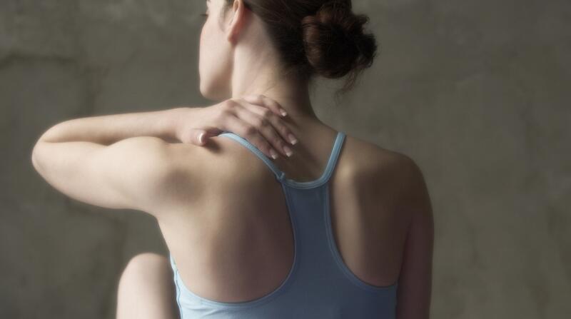 woman touching upper back