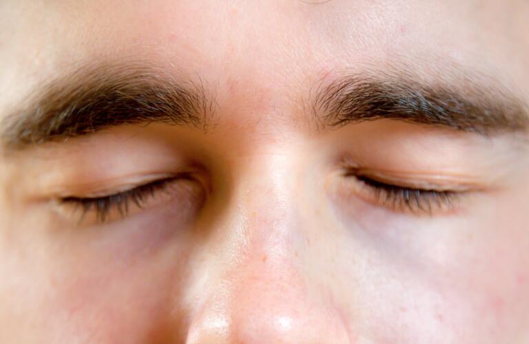 close up view of Caucasian man blinking eyes
