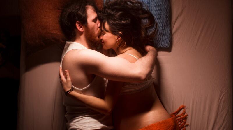 Male lying in bed with a pregnant female, snuggling