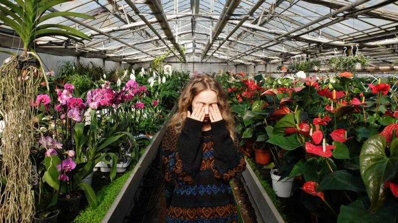 a girl is feeling dizzy in a greenhouse
