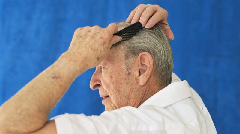 An older man combing his hair