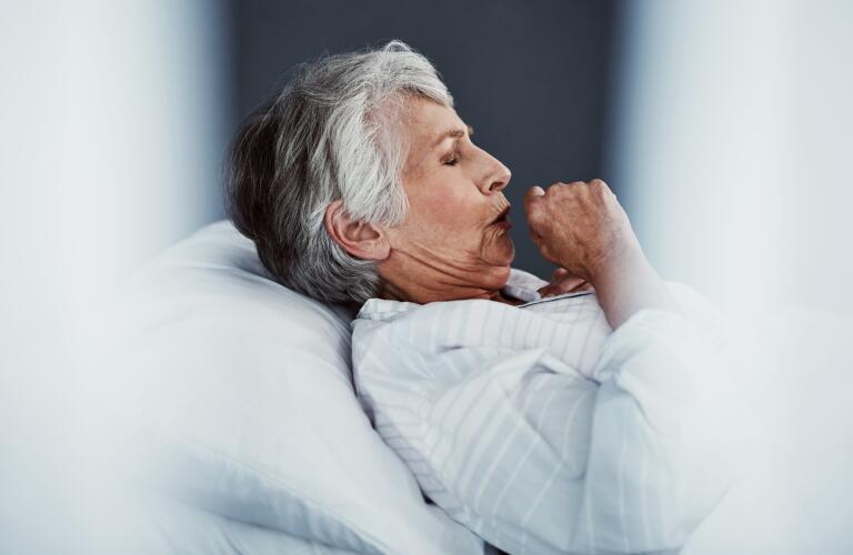 Senior Caucasian woman in bed coughing