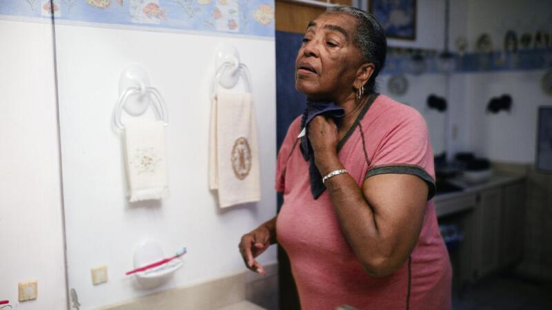 A woman is holding a towel against her neck.