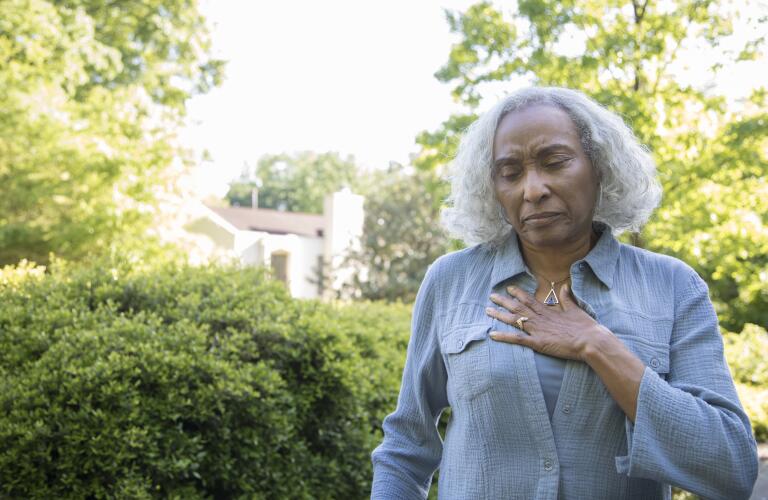 Older African American woman outside feeling chest pain or arrhythmia