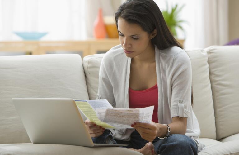 Hispanic woman paying bills online with laptop