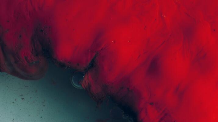 There is a close-up photo of red blood over a dark green background.