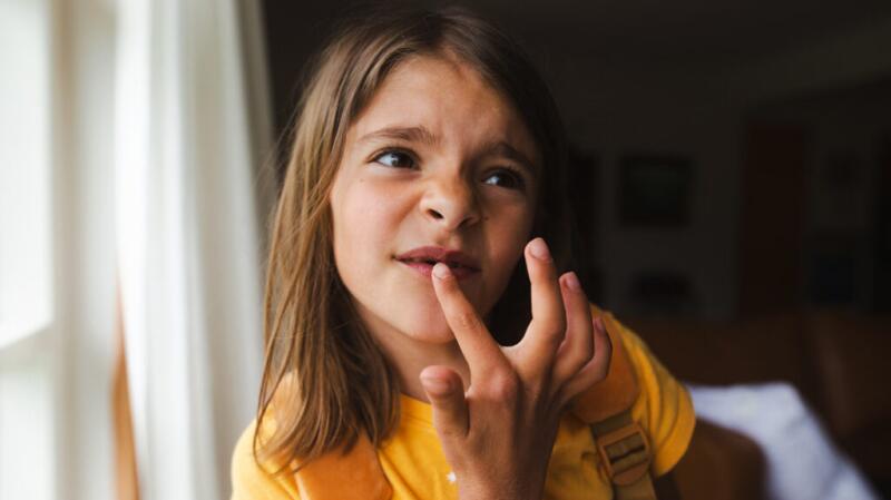 A child touching one of their front teeth
