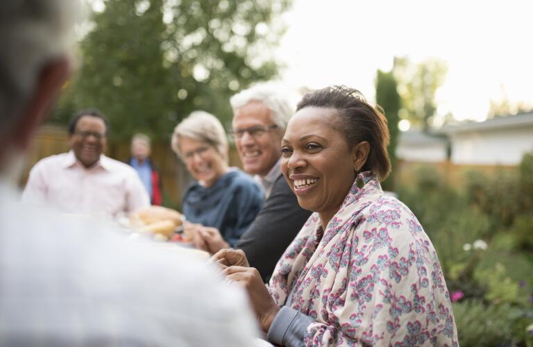 senior woman enjoying dinner outside with friends