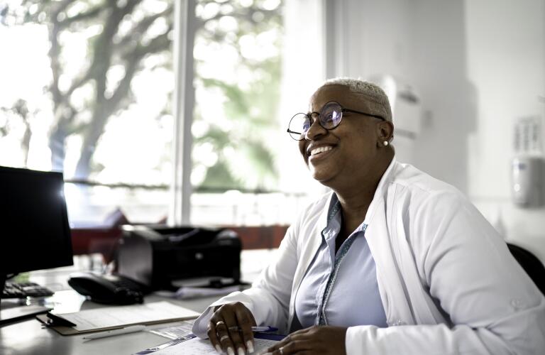 Happy mature doctor woman smiling to patient on medical appointment
