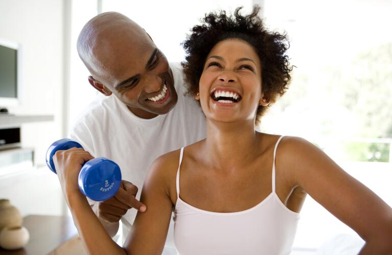 Man smiling at woman lifting weights