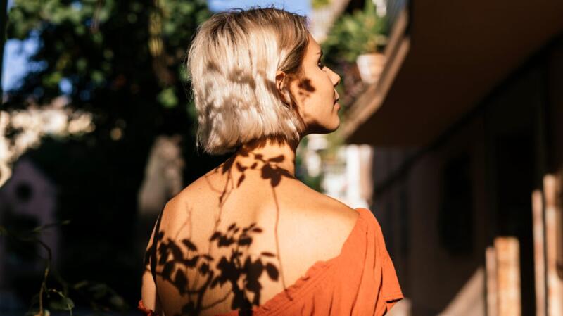 Plants are making a shadow on a woman's back.