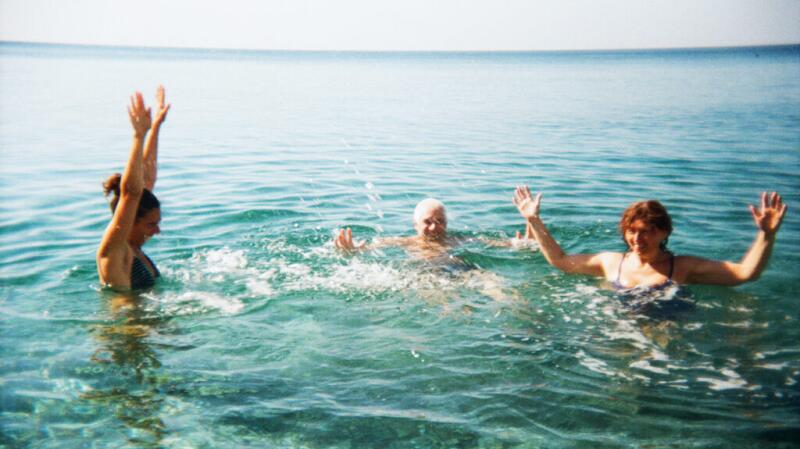 Three adults swimming in the ocean on a sunny day