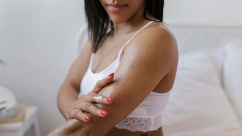 A woman applying moisturizing cream to her arm