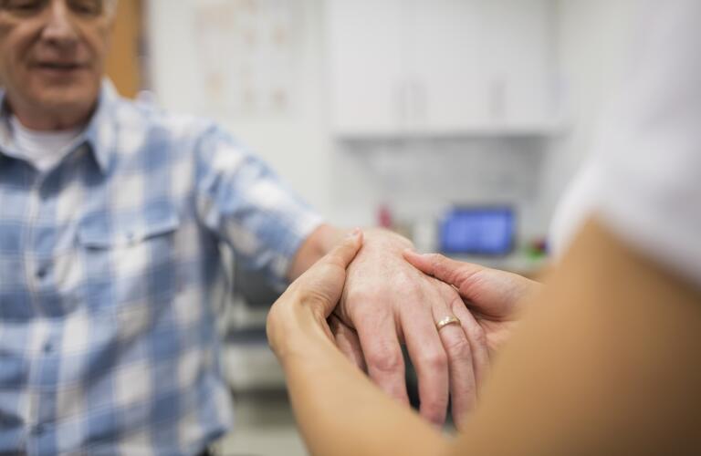 closeup of doctor or physical therapist feeling back of patient hand