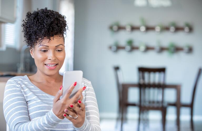 African American woman in her 30s looking at mobile phone at home