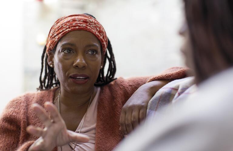 African American woman in conversation with friend on couch