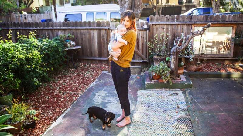A woman standing outside and holding her newborn baby