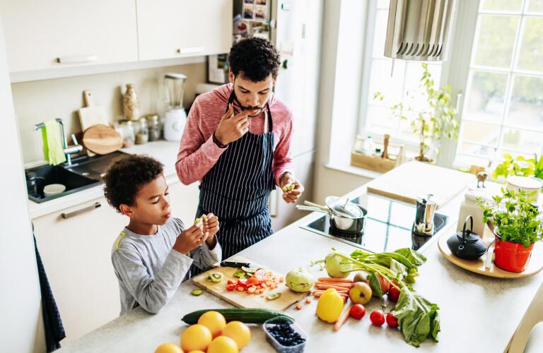 African American father and young son cooking together in kitchen