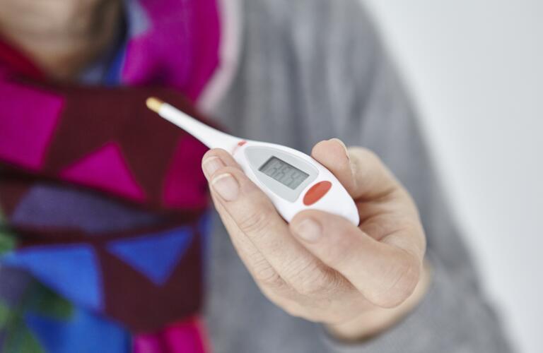 Close up of woman's hand holding thermometer