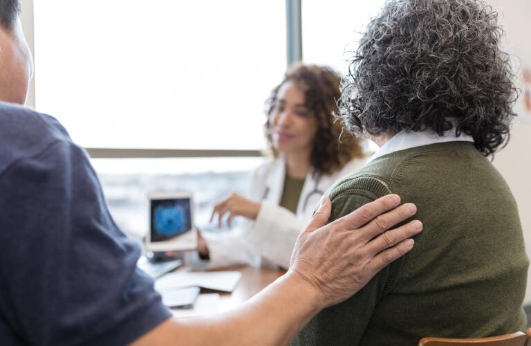 Husband comforts wife during appointment with a neurologist