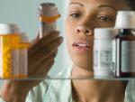 Woman looking at medication bottle in medicine cabinet