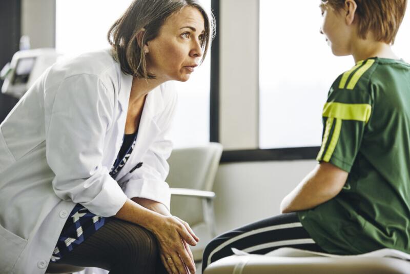 Smiling doctor talking to boy in exam room