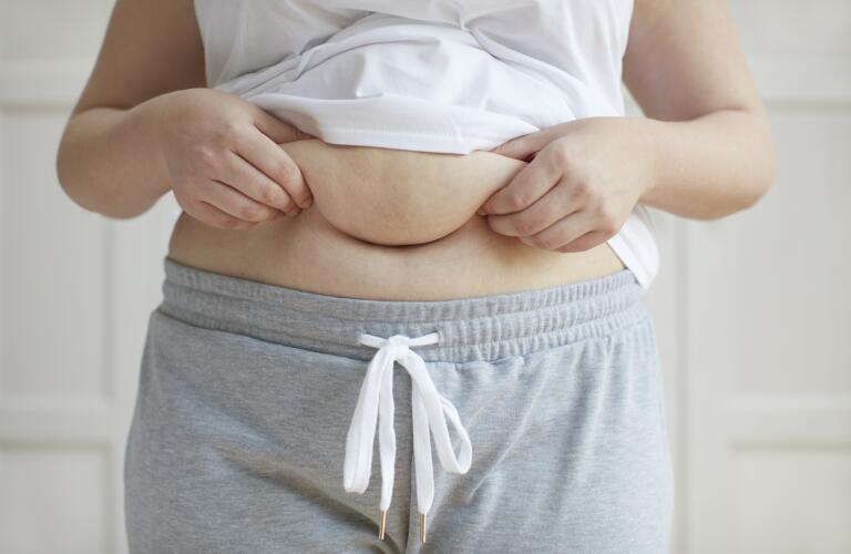 Unseen Caucasian woman holding belly fat