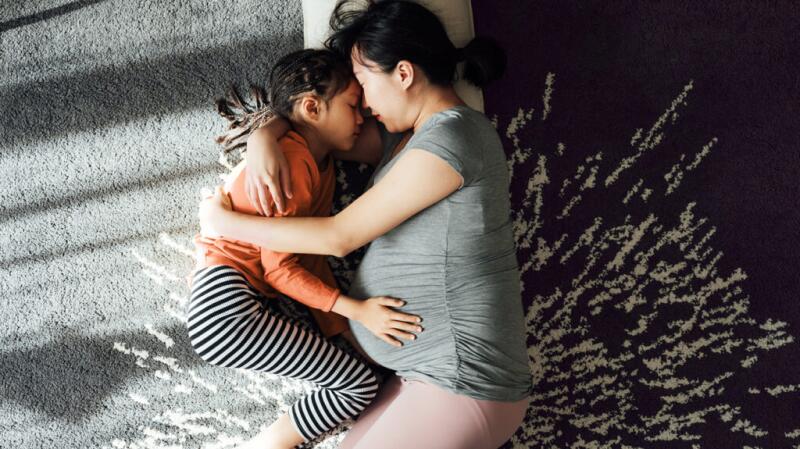 Pregnant mother hugging child
