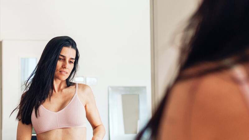 Female in a pink sports bra looking in the mirror