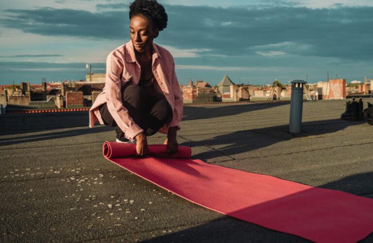 a woman is rolling out an exercise mat outside