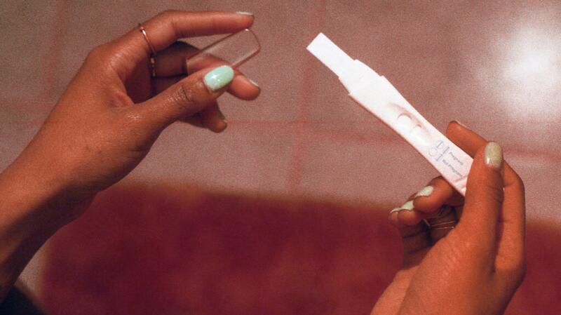 A closeup of a woman's hands holding a pregnancy test