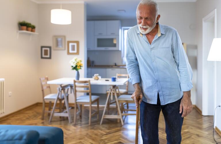 Senior man walking with cane in his home