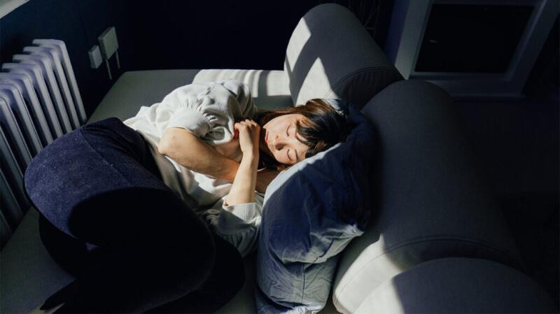 Person lying on a couch with the sun coming through a window