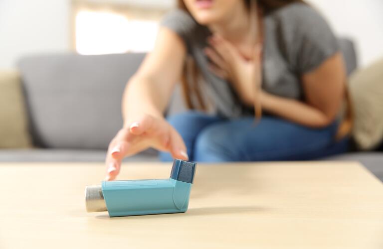 young woman reaching desperately for asthma inhaler
