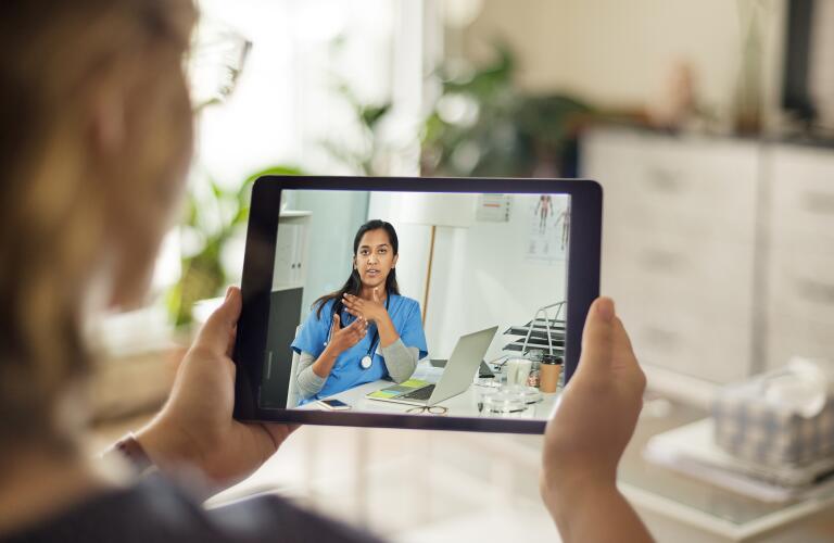 Over the shoulder shot of a patient talking to a doctor using a digital tablet