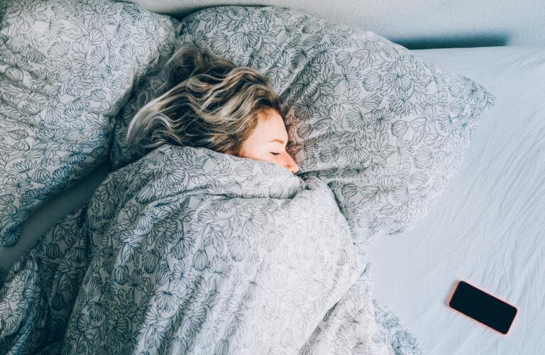 Young Caucasian woman sleeping under heavy blanket