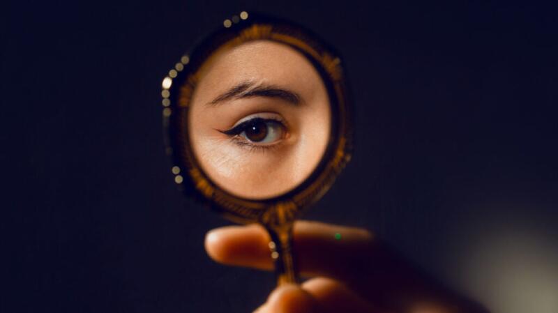 Woman's eye visible in handheld mirror