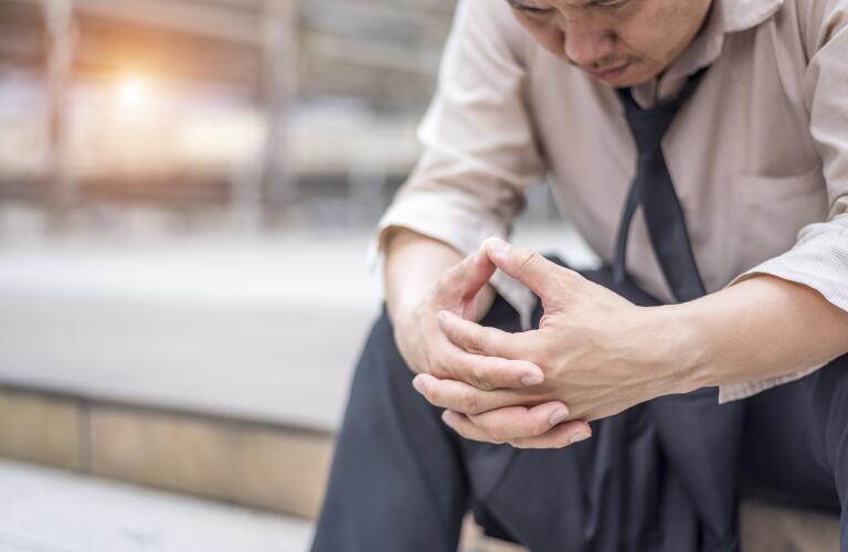 Asian American man sitting with head down looking sad or stressed