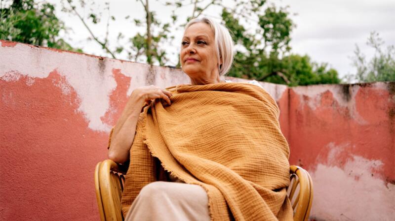 middle aged woman sitting outdoors with a shawl around her shoulders
