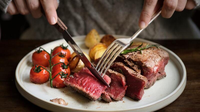 A person cutting into a steak on their plate