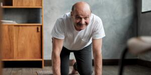 senior man practices yoga asana marjariasana or cat-cow pose at home 