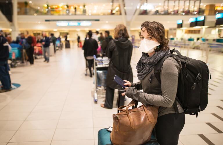 At the airport with a face mask standing in socially distanced line to check in