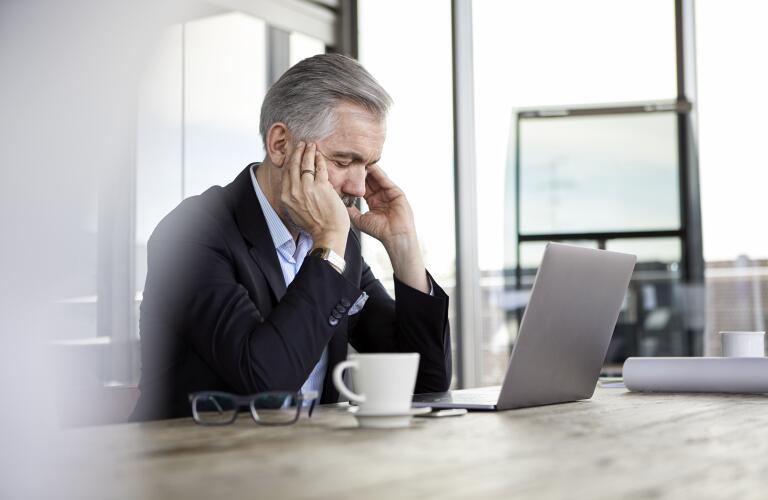 Businessman with headache sitting at desk in office