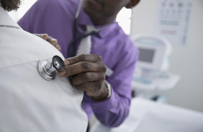 doctor placing stethoscope on patient's back