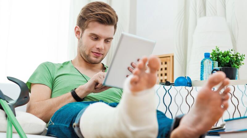Young man with broken leg at home