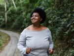 smiling African American woman walking or jogging through forest trail