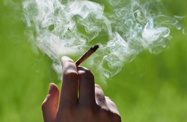 Close-up of hand holding smoking marijuana cigarette