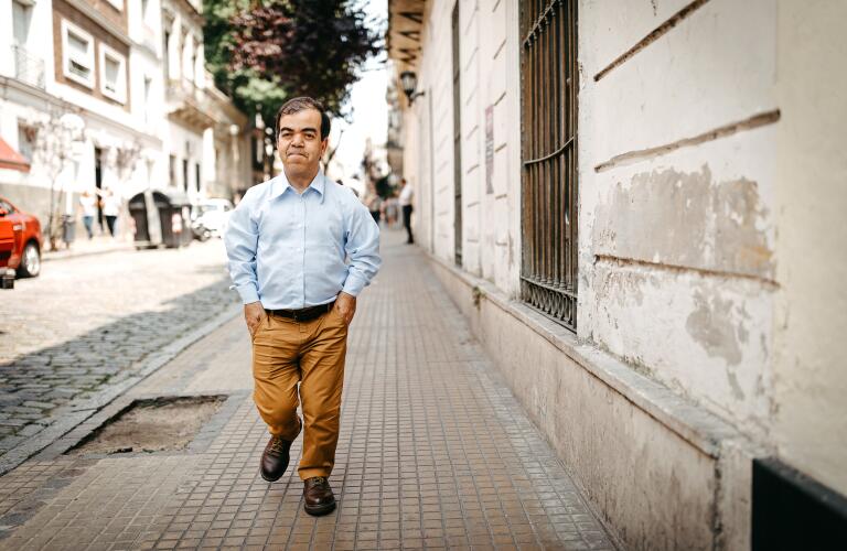 Dwarfish man walking with hands in pockets on city street