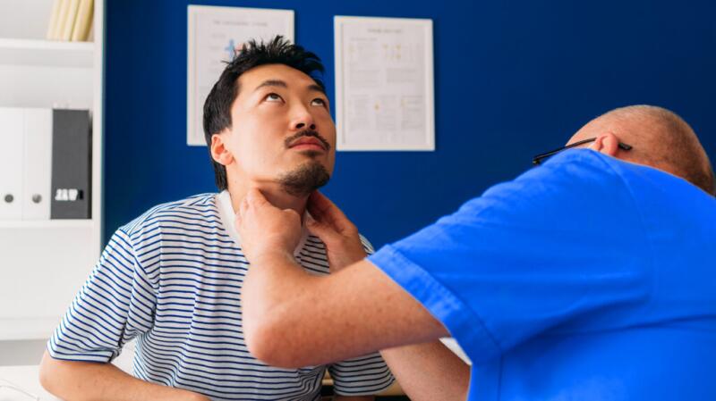 A doctor is checking a person's throat.