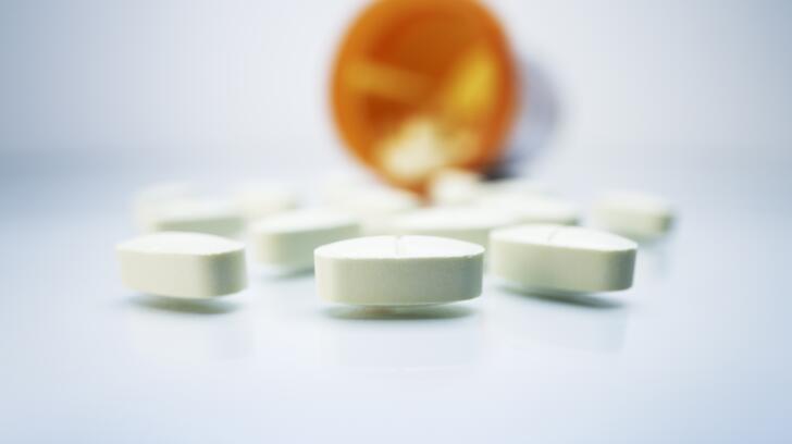 white oval pills spilling out of prescription bottle